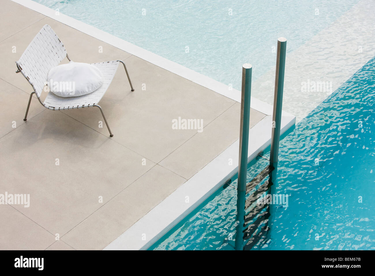 Chair with cushion at edge of pool near ladder Stock Photo Alamy