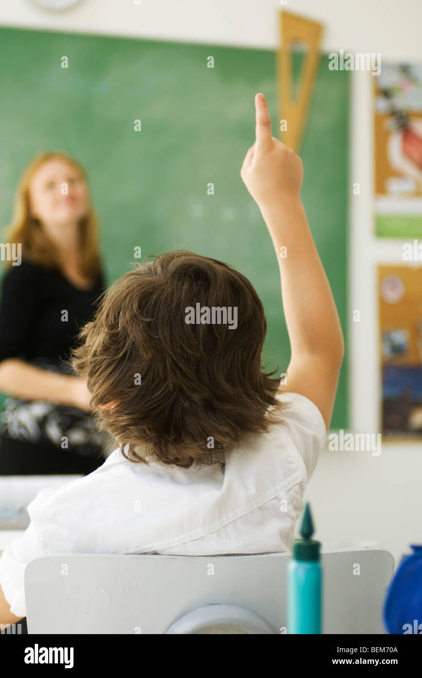 Elementary student raising hand in class, rear view Stock Photo