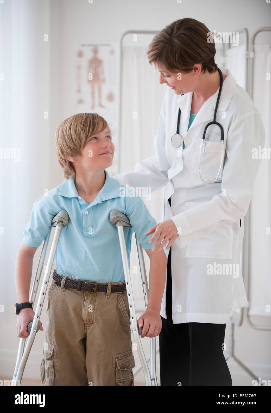 Female doctor assisting boy on crutches Stock Photo