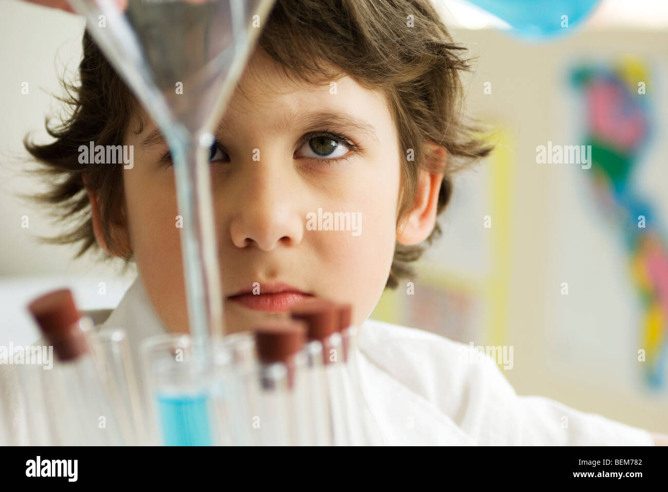 Boy pouring liquid into test tube using funnel Stock Photo Alamy