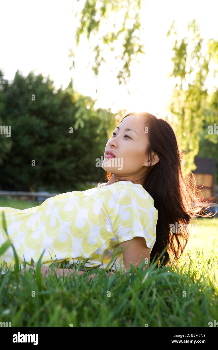 Woman lying in grass, looking away Stock Photo