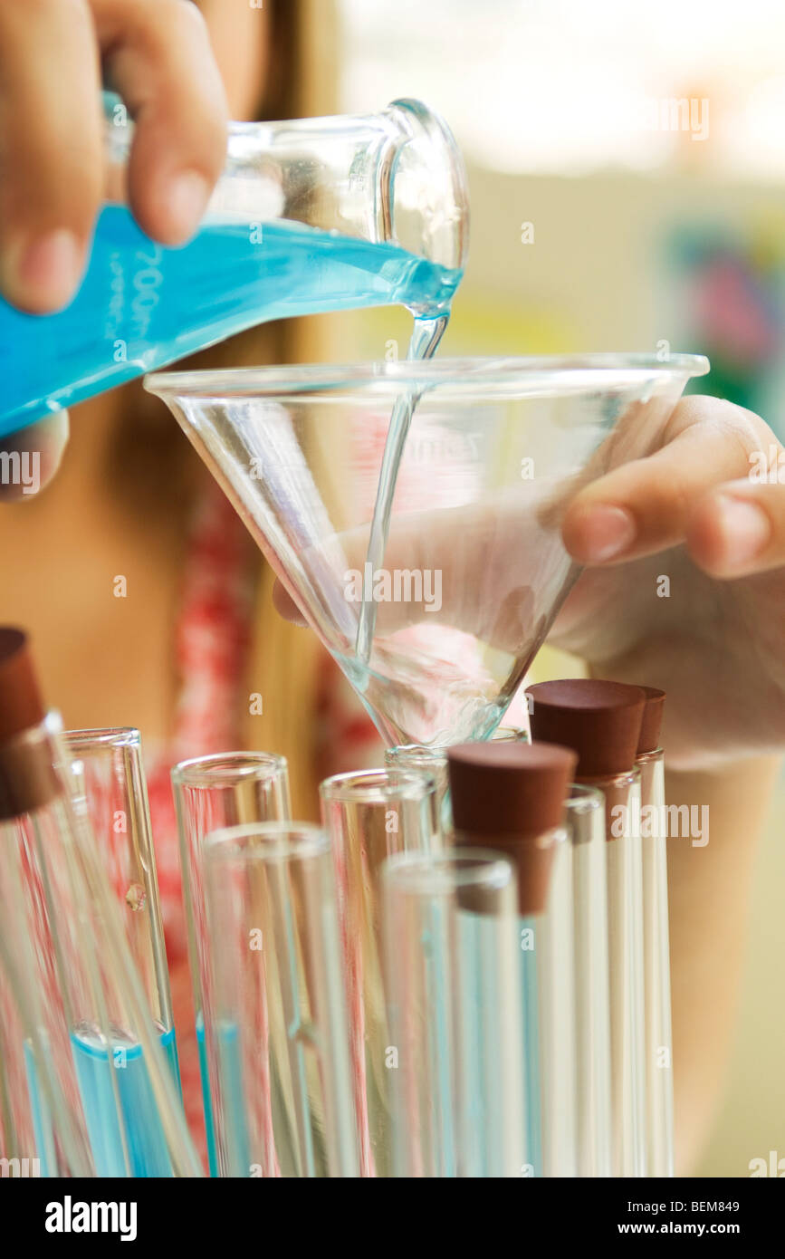 Elementary student transferring liquid from beaker to test tube using funnel, close-up Stock Photo