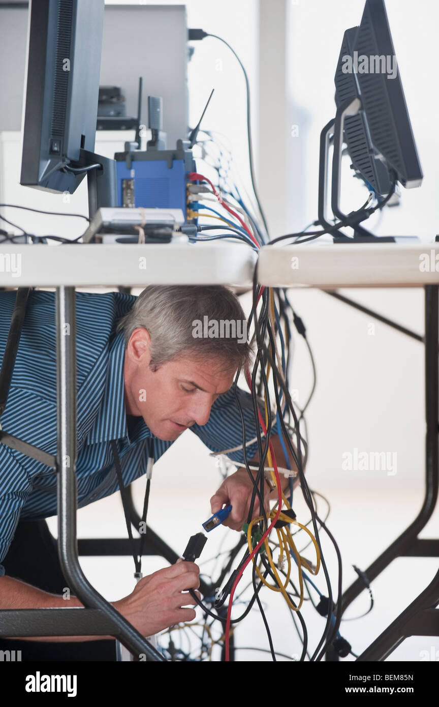 Man under table working on networked computers Stock Photo