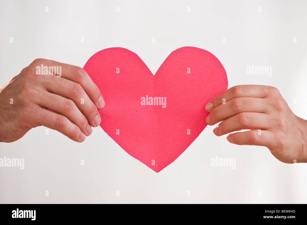 Two hands holding paper heart Stock Photo