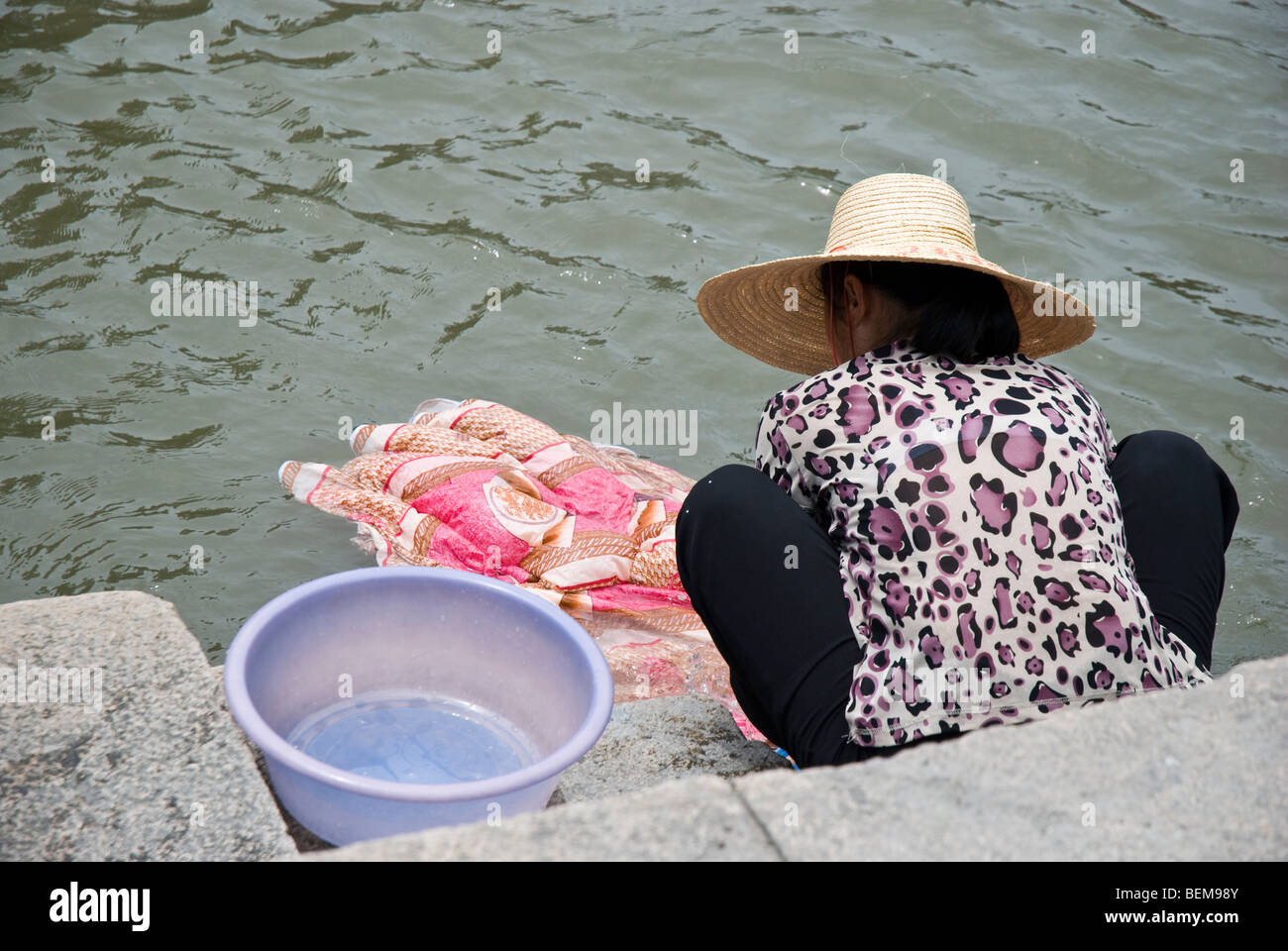 Chinese woman hand washing cloth in canal water Xitang is an ancient scenic town in Jiashan County, Zhejiang Province, China. Stock Photo