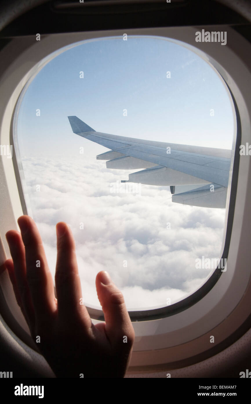A passenger's hand on an airplane window. The airplane is Airbus A340