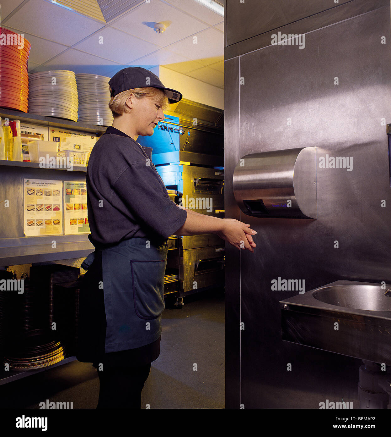 Restaurant kitchen worker drying hands using a hygienic hot air hand