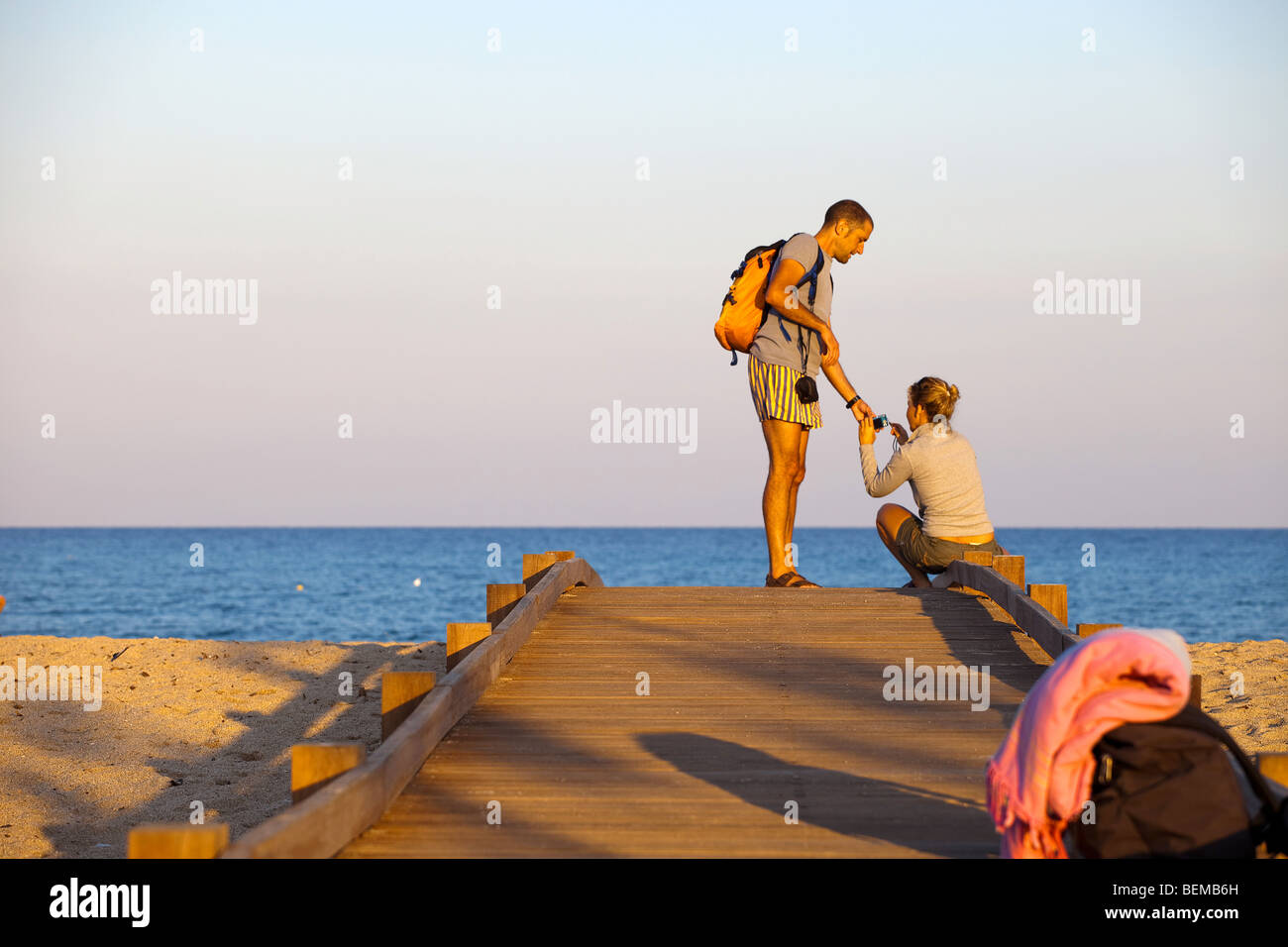 San Teodoro beach at the sunset with people. Couple on the beach at sunset. Backpaking in Italy, backpack. Stock Photo