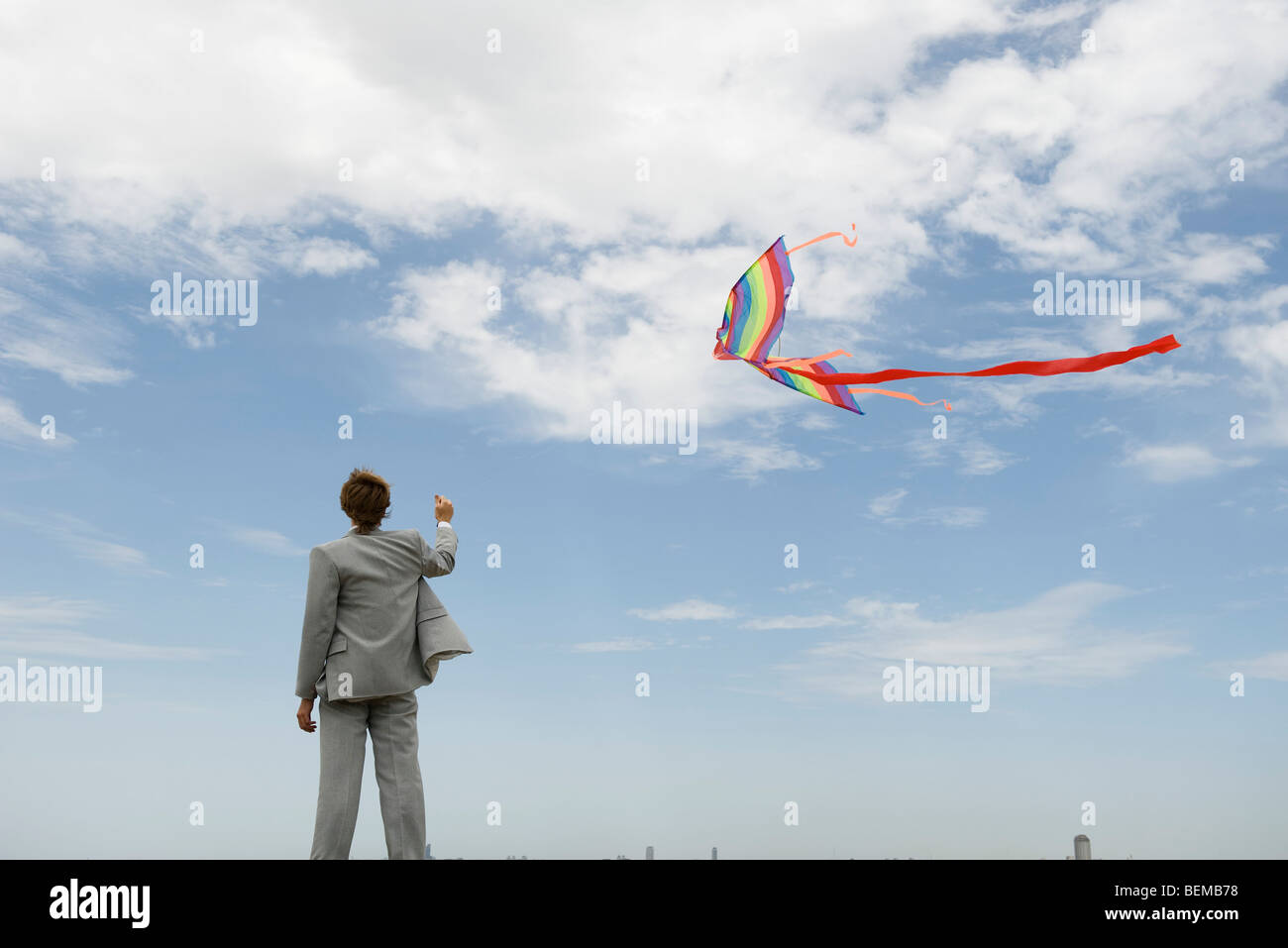 Businessman flying kite in field, rear view Stock Photo