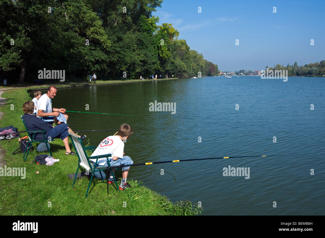 Family, father and sons with fishing rods angling in lake Donkmeer, East Flanders, Belgium Stock Photo