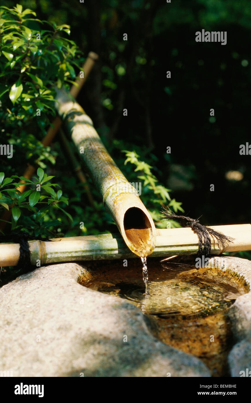 Water trickling from bamboo pipes into stone wash basin, Japan Stock Photo