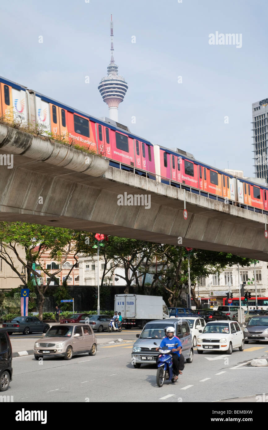 A road junction with a RapidKL train traveling on an elevated railway in downtown Kuala Lumpur, Malaysia. Stock Photo