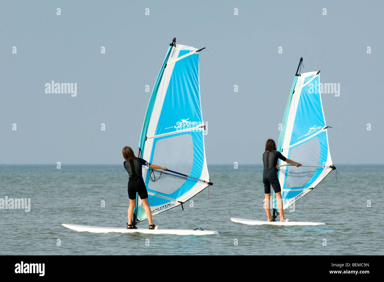 Two young girls windsurfing along the North Sea coast Stock Photo