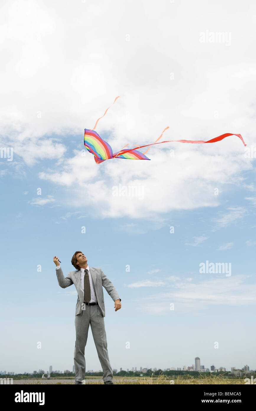 Businessman flying kite in field Stock Photo