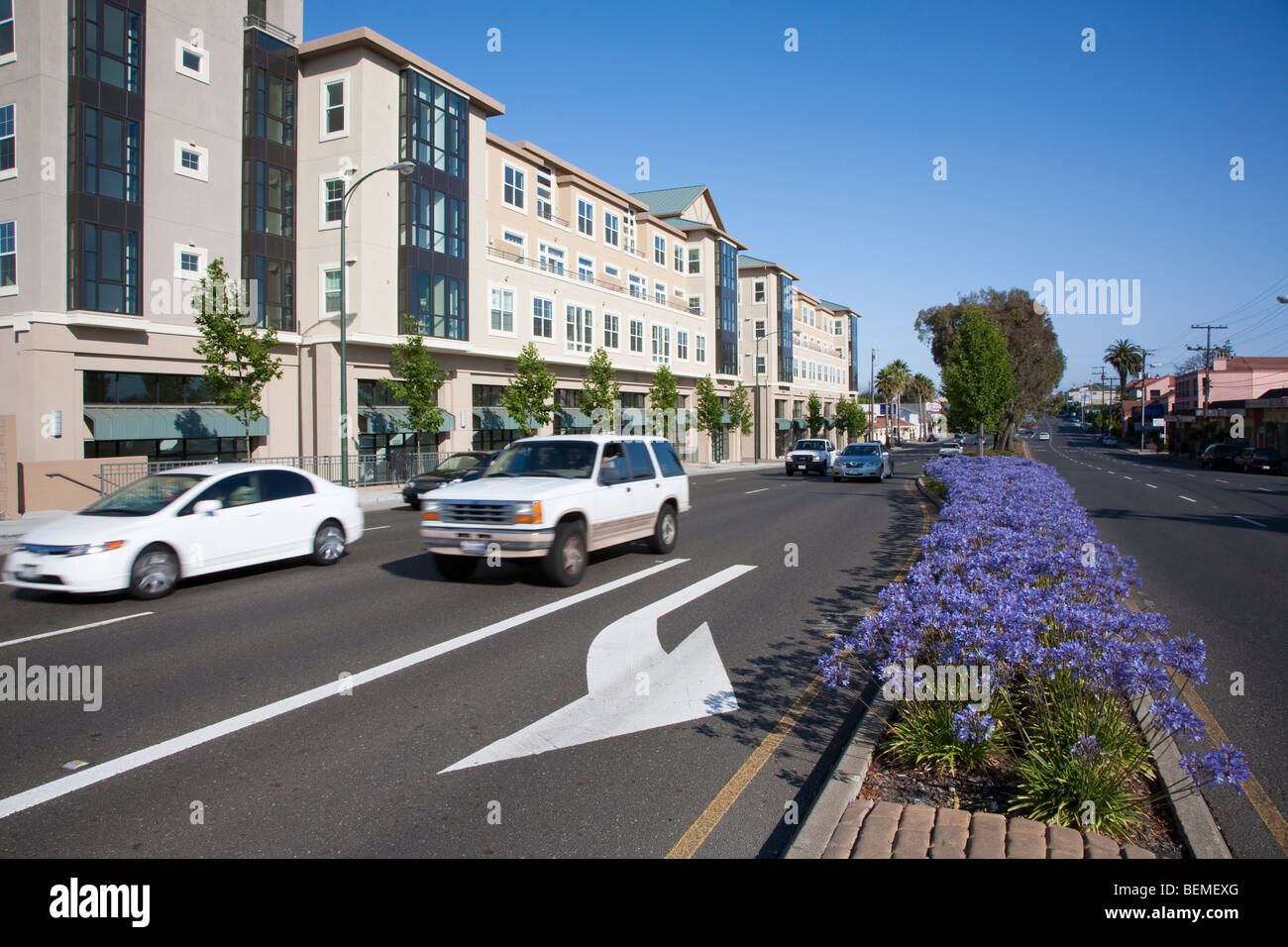 Cars on El Camino Real pass a mixed use housing development. Landscaped
