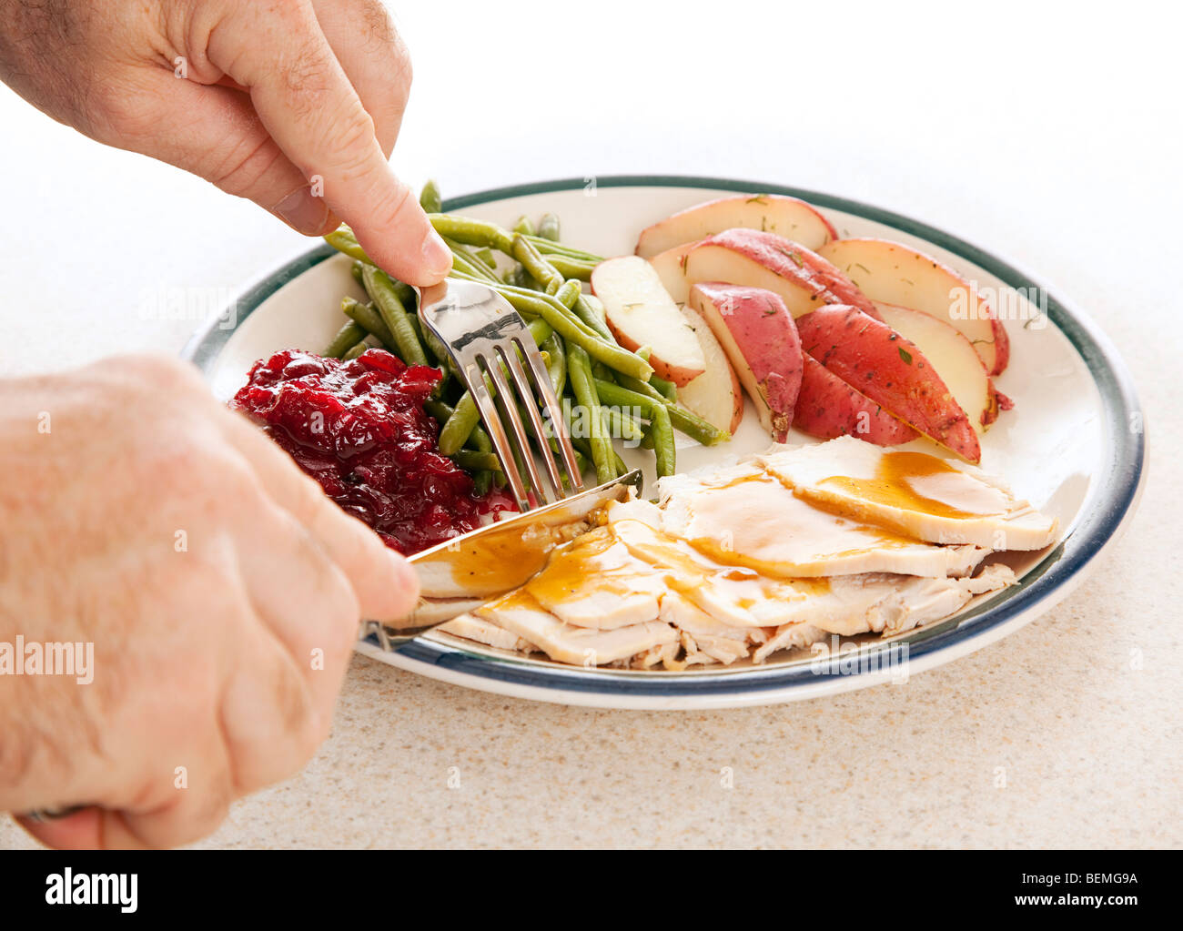 Man's hands eating a delicious turkey dinner for Thanksgiving or other meal.  Stock Photo