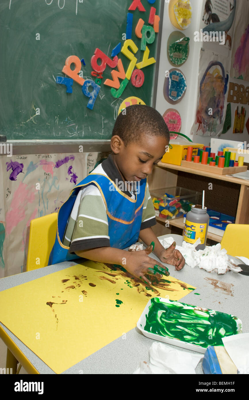African-American preschool boy finger painting in the classroom Stock Photo