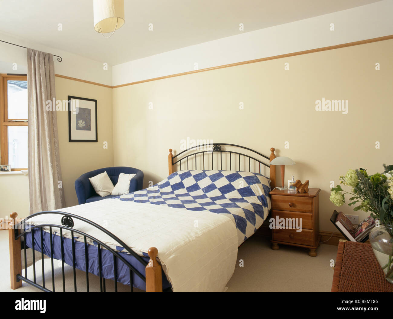 Blue White Quilt With Plain Cream Quilt On Metal Bed In