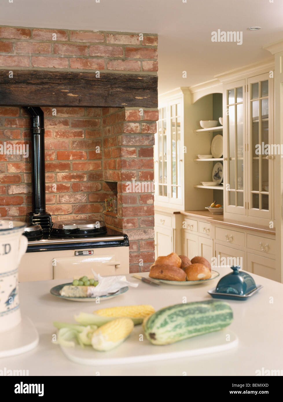 Vegetables on table in cottage kitchen with Aga oven in exposed brick fireplace Stock Photo