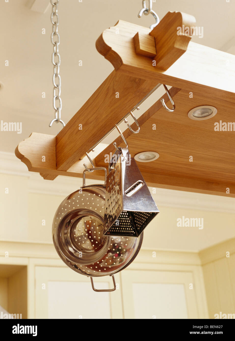 Closeup of stainless steel colander and grater on suspended wooden