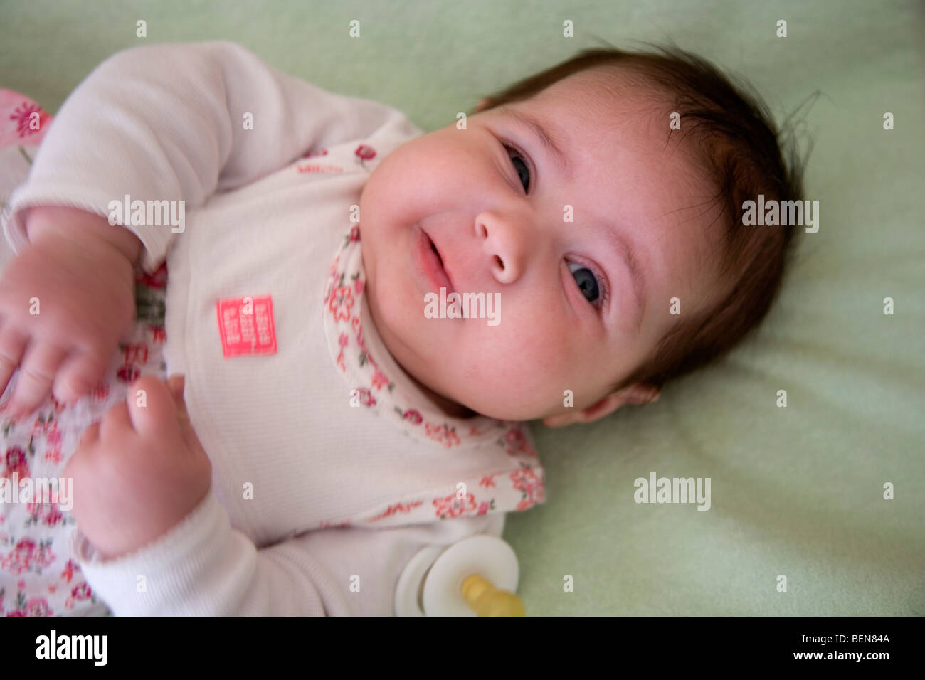 Baby lying down pulling funny face Stock Photo Alamy