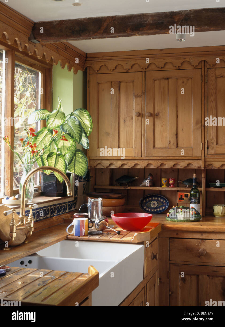 Tall houseplant on windowsill above double Belfast sink in kitchen