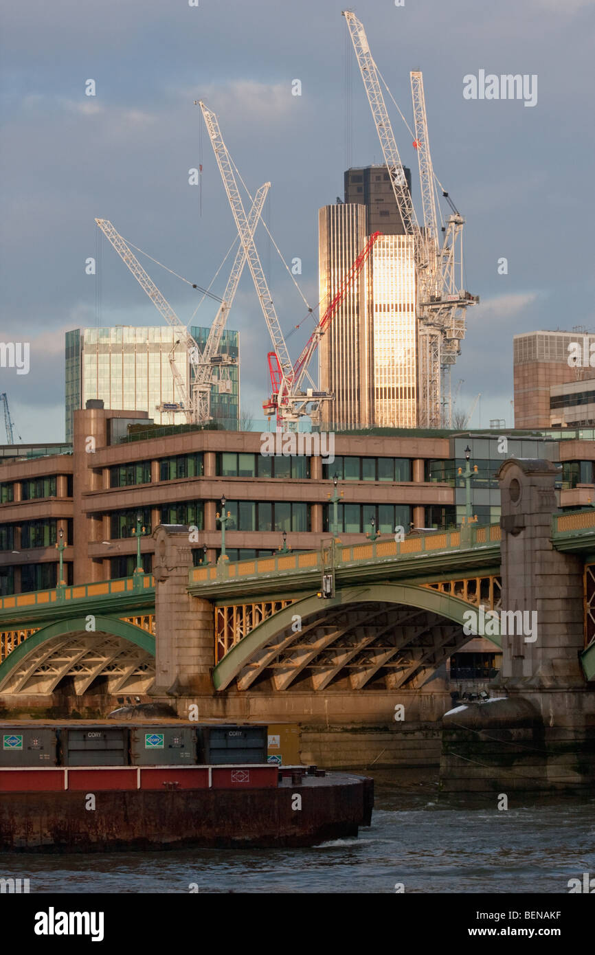 Waste containers pass under Southwark Bridge on a barge in London, February 2009. Natwest Tower & construction cranes behind. Stock Photo