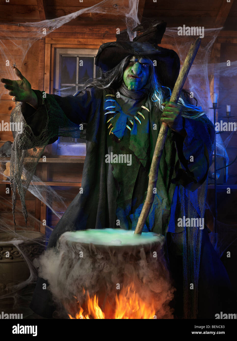 License available at MaximImages.com - Scary old witch stirring potion in a cauldron inside her cabin on Halloween Stock Photo