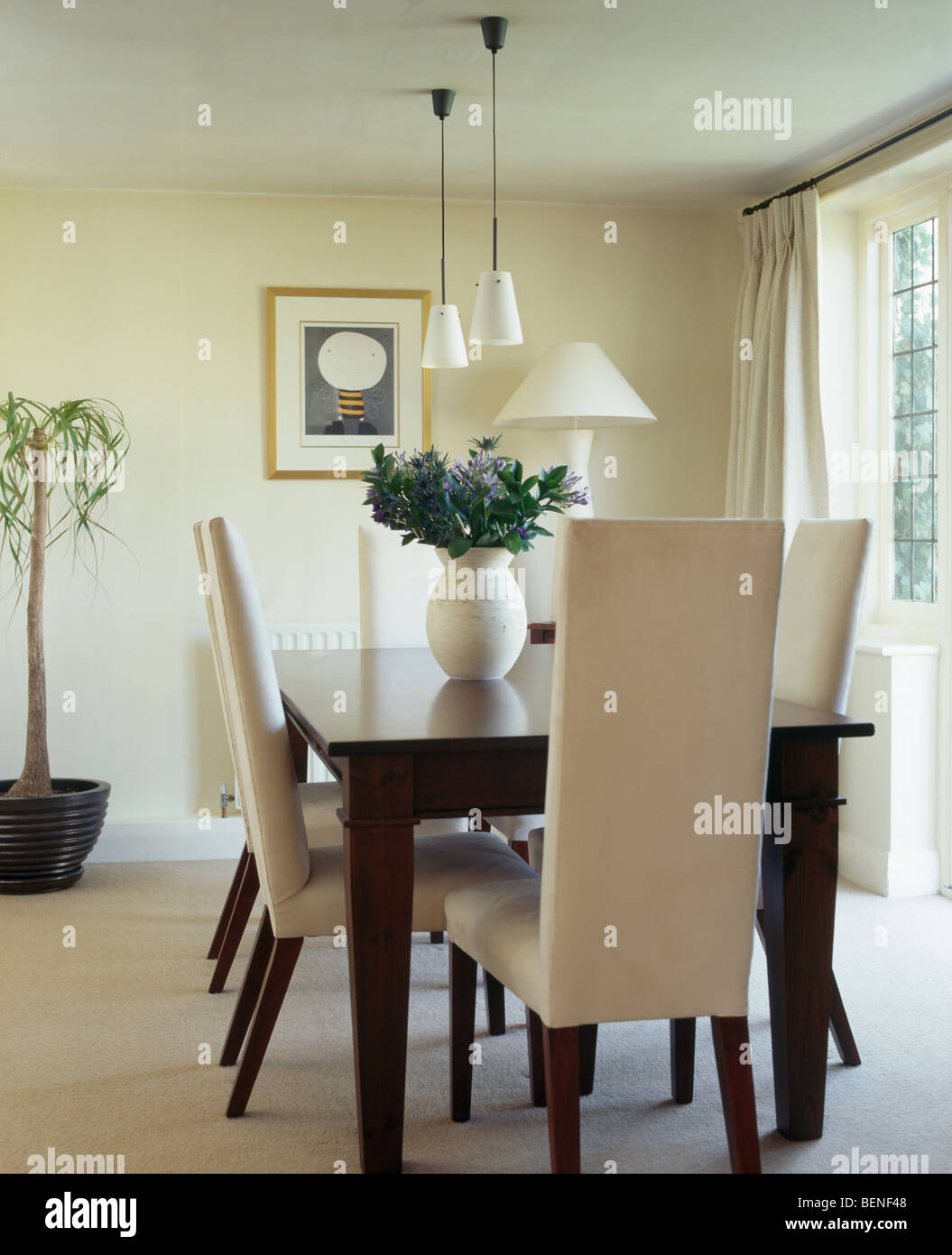 Cream upholstered highback chairs and dark wood table in modern cream dining room with cream