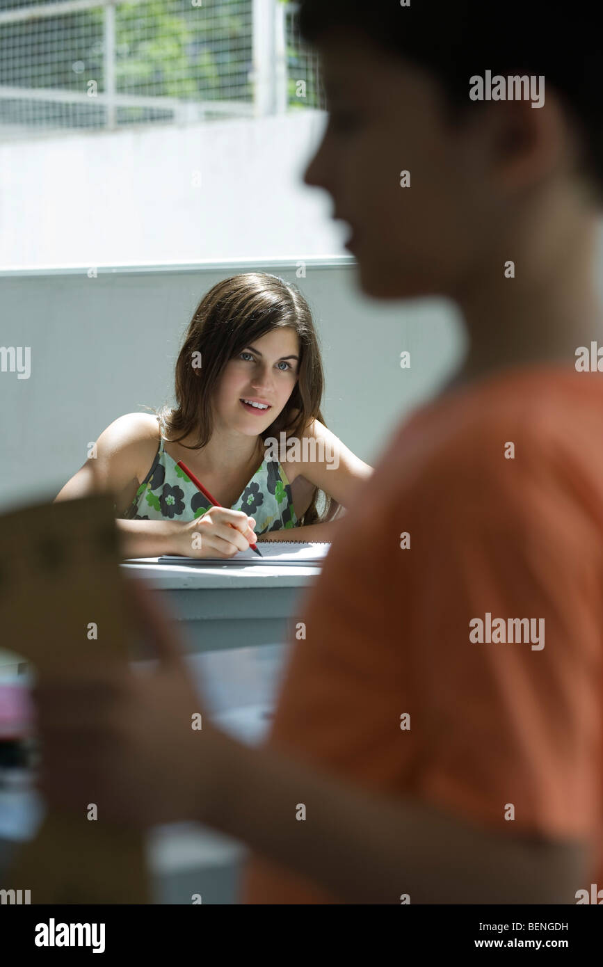 Teenage girl doing homework, boy in foreground Stock Photo