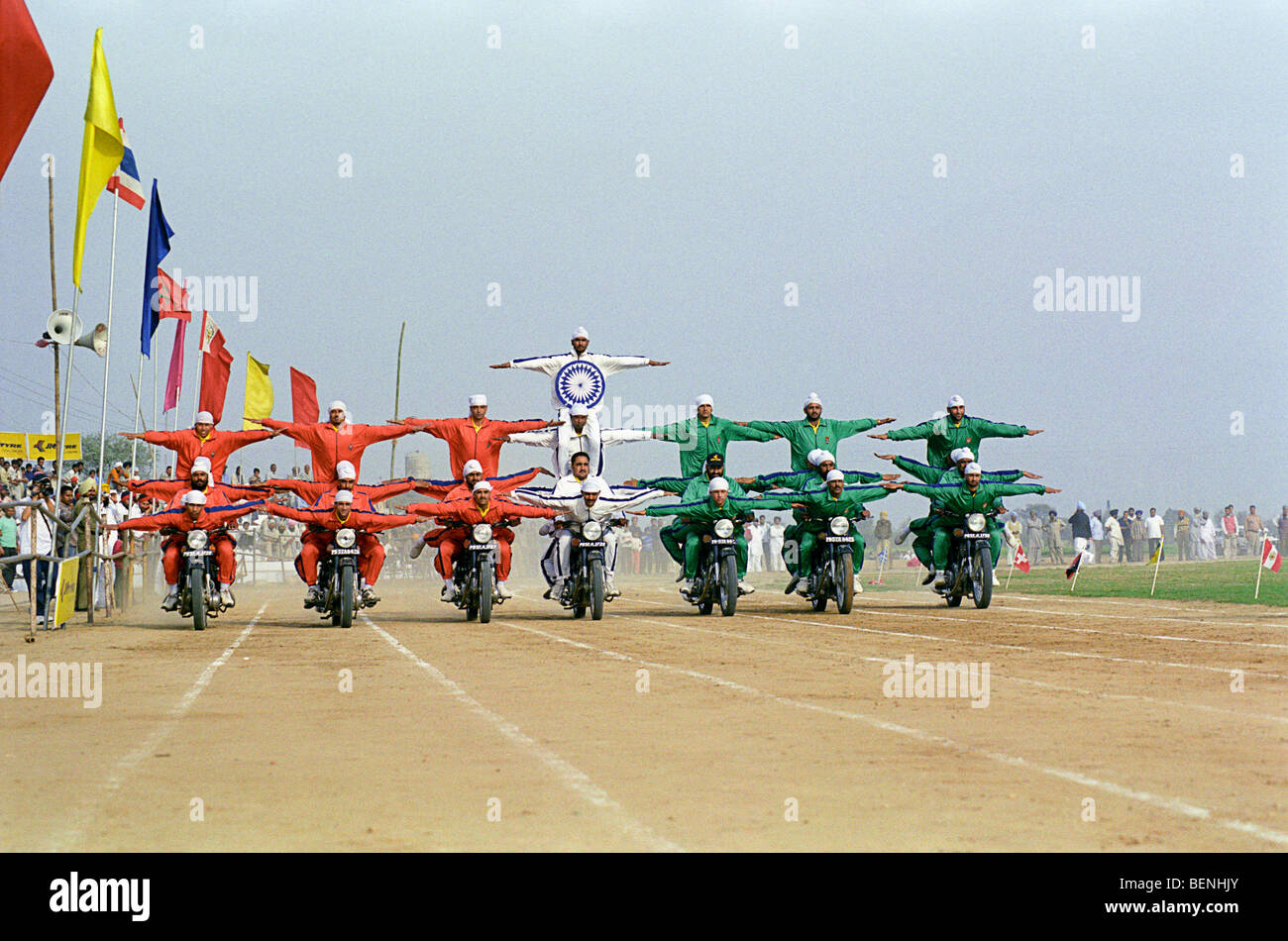 Stuntmen making the colours of the Indian Flag on motorcycles at rural Olympic games in Kila Raipur Punjab India Stock Photo