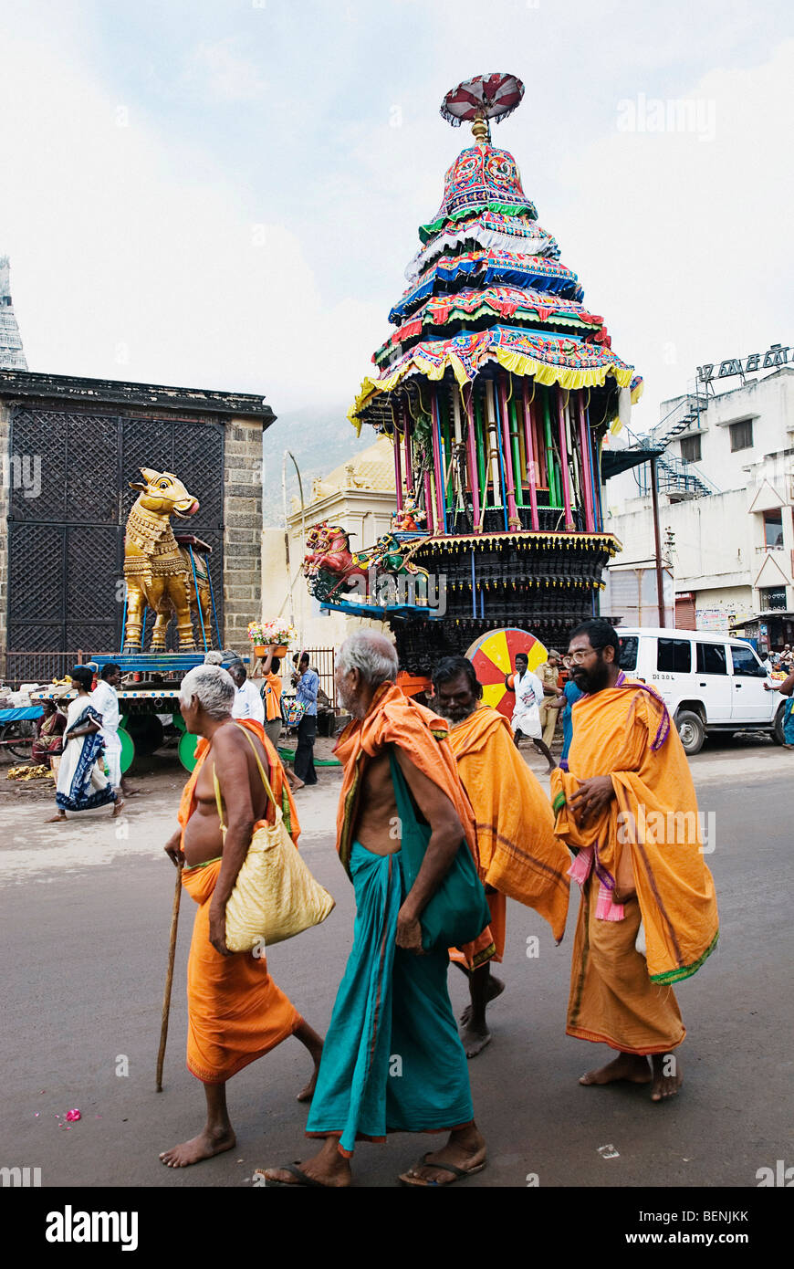 Holy men walking down the street with the Temple Chariot in the background during the Karthigai Deepam Festival celebrated in Stock Photo