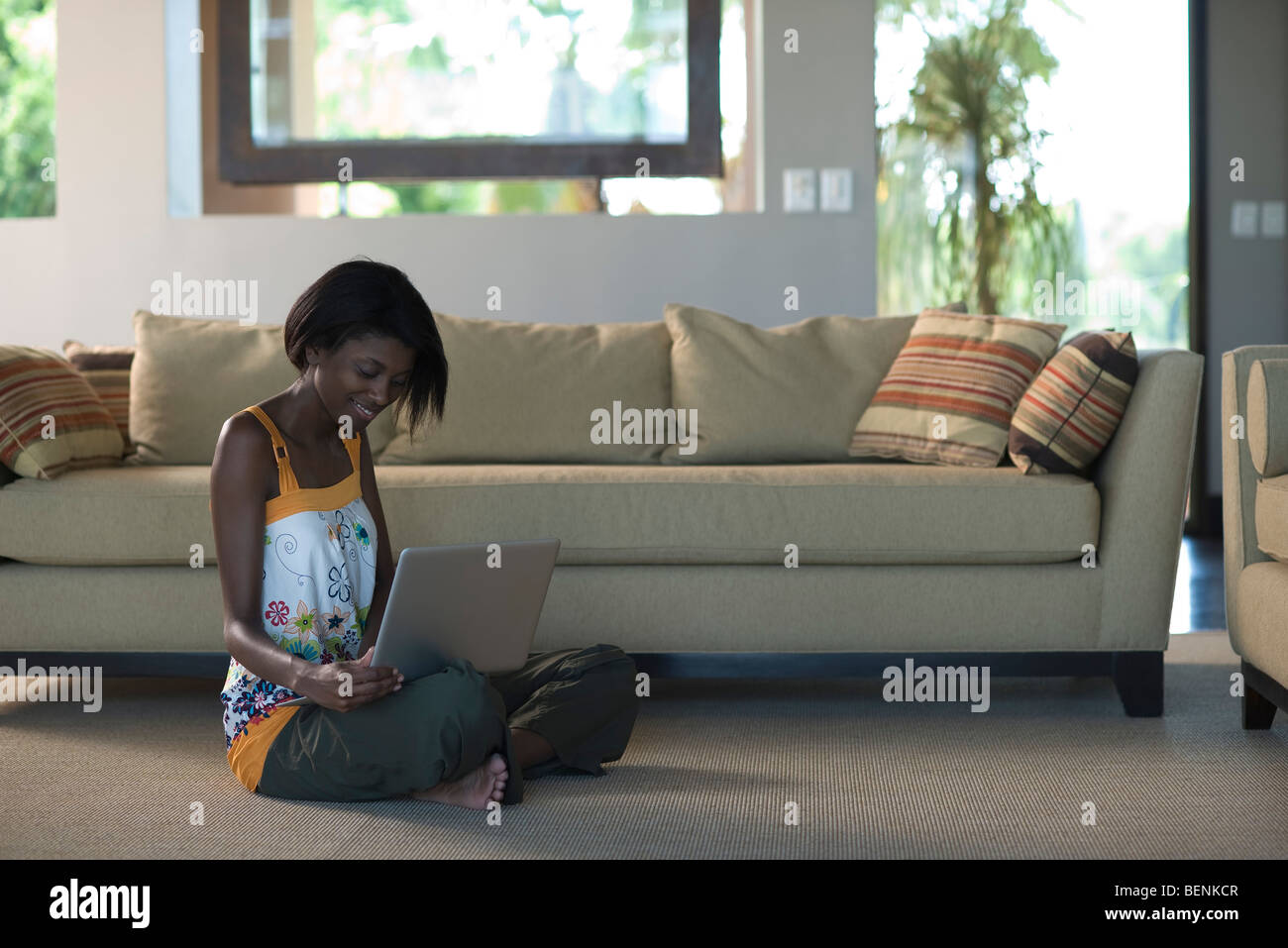 Young woman sitting on living room floor using laptop computer Stock Photo