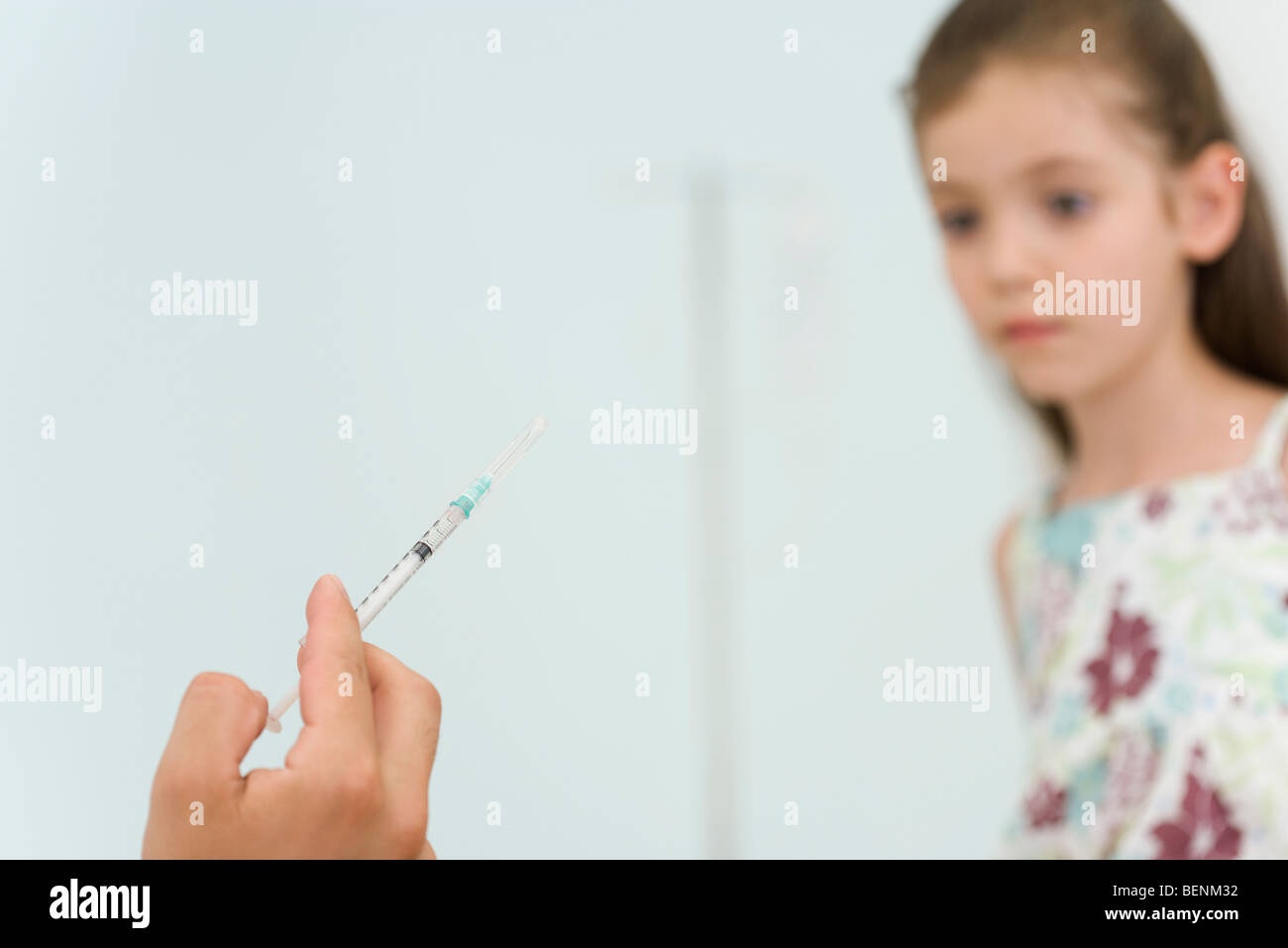 Doctor holding syringe, preparing to vaccinate little girl, cropped Stock Photo
