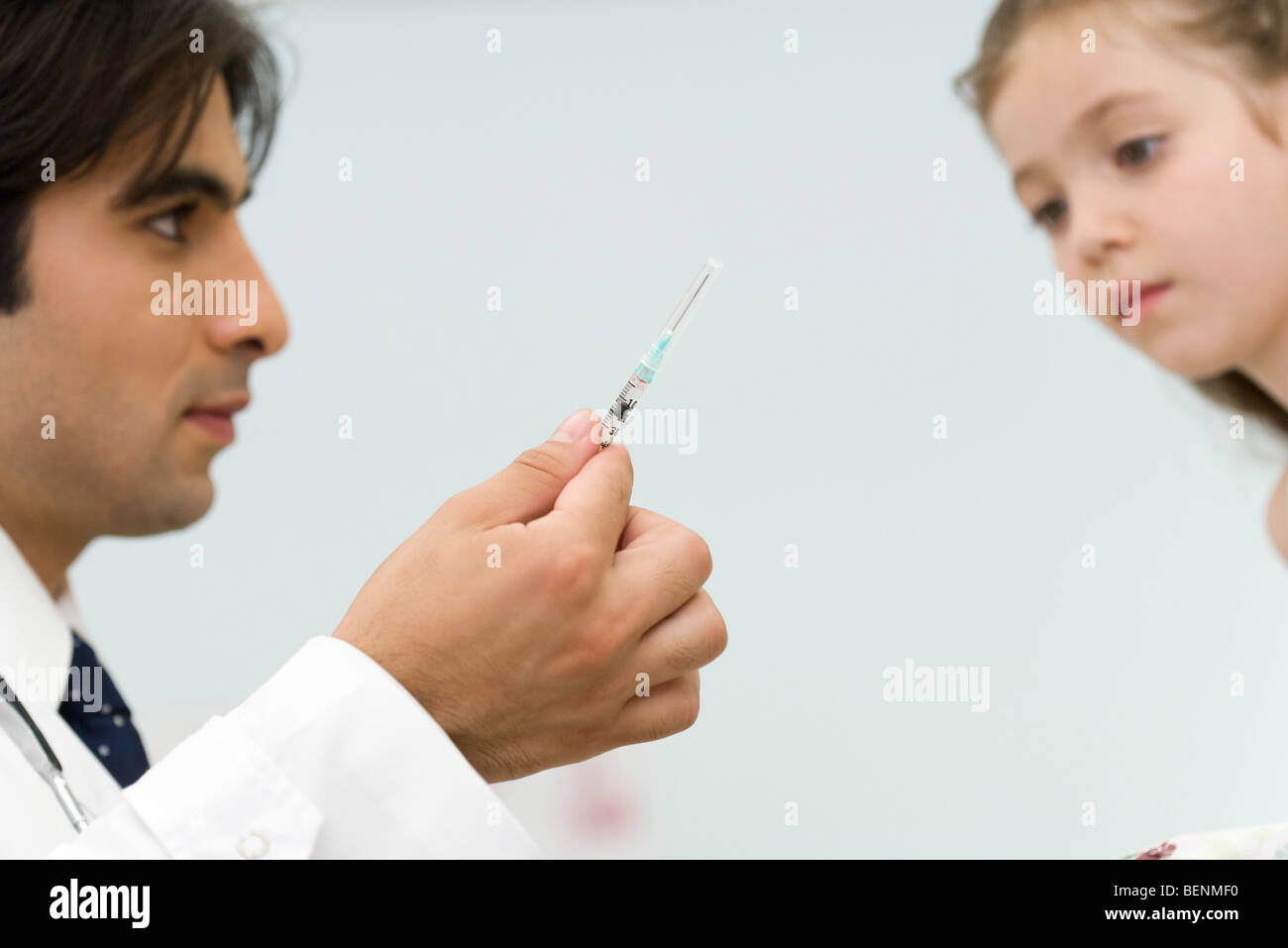 Pediatrician showing little girl syringe Stock Photo
