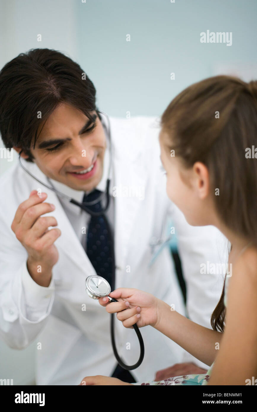 Doctor showing little girl how to use stethoscope Stock Photo ...