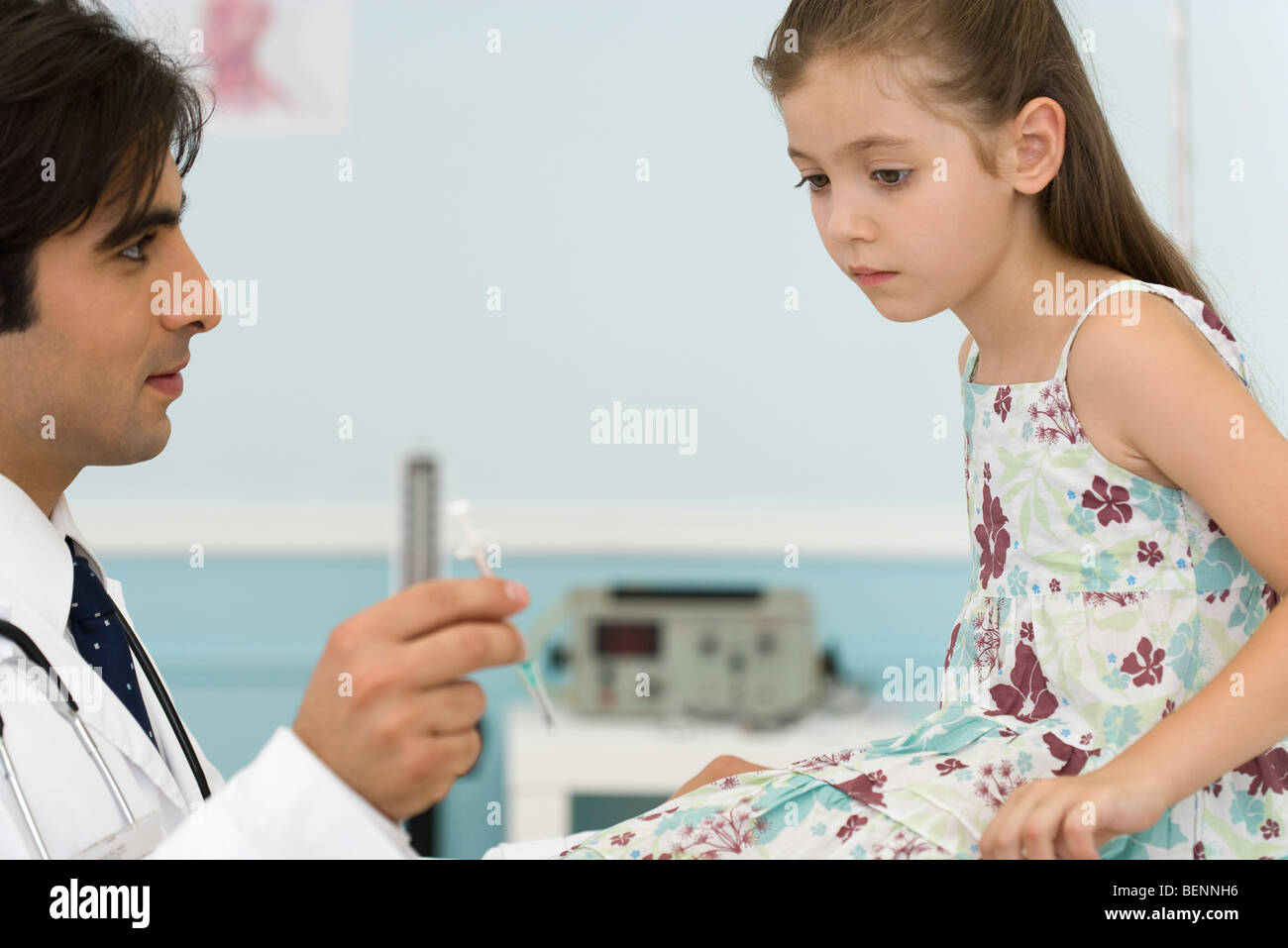 Pediatrician explaining syringe to little girl Stock Photo