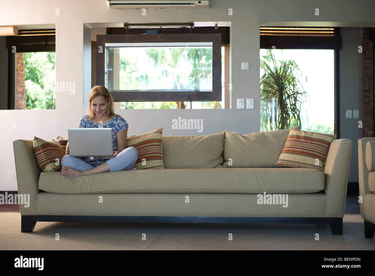 Young woman sitting on sofa using laptop computer Stock Photo - Alamy