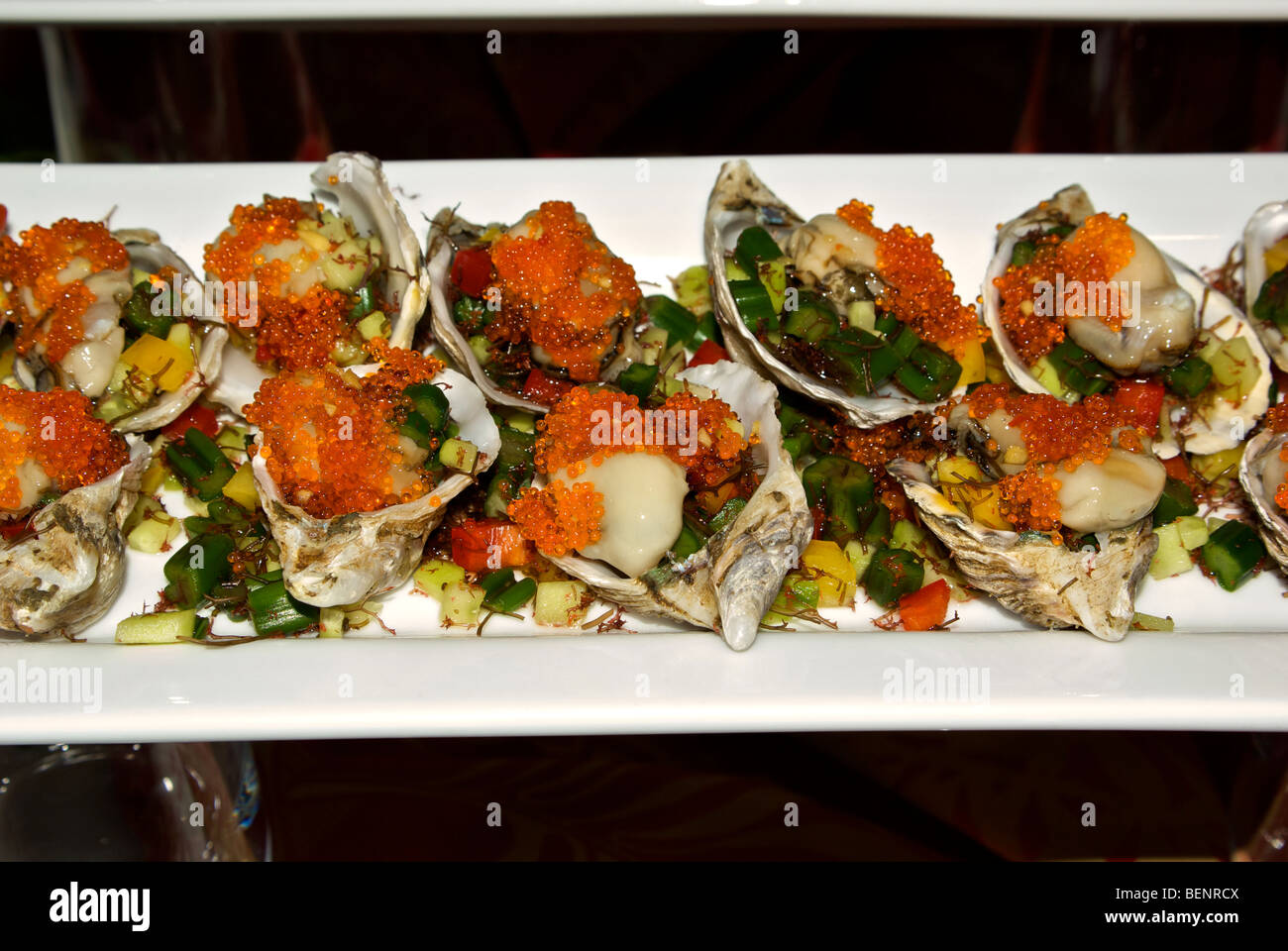Marinated Hawaiian oysters with orange flying fish roe garnish on half shell appetizers Stock