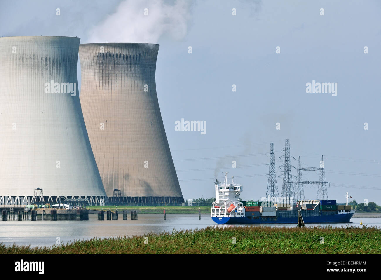 Container ship on the river Scheldt in front of the cooling towers of the nuclear power plant at Doel, Belgium Stock Photo
