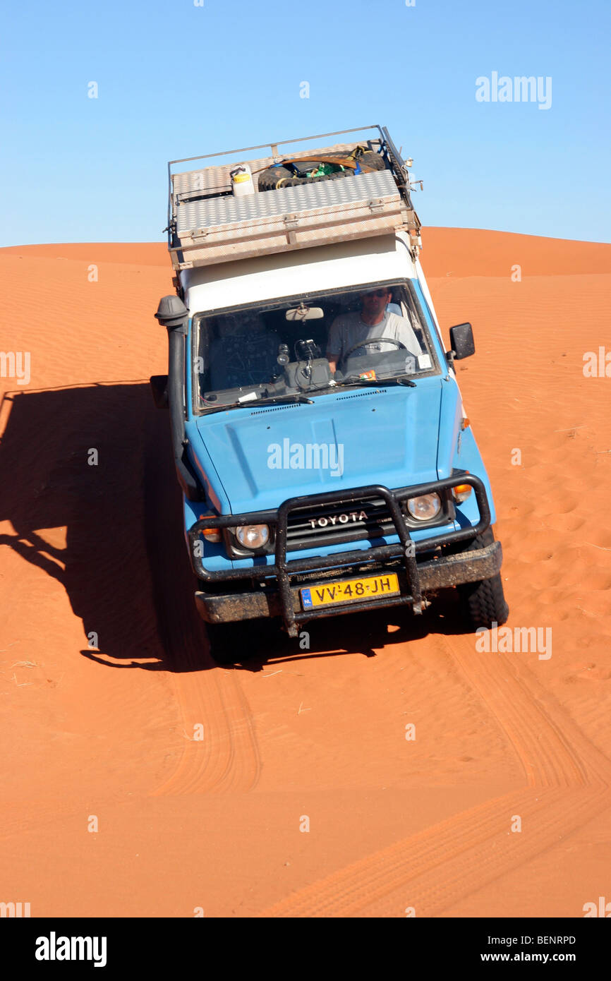 Offroad fourwheel drive vehicle driving over red sand dune in the Namib desert, Namibia, South