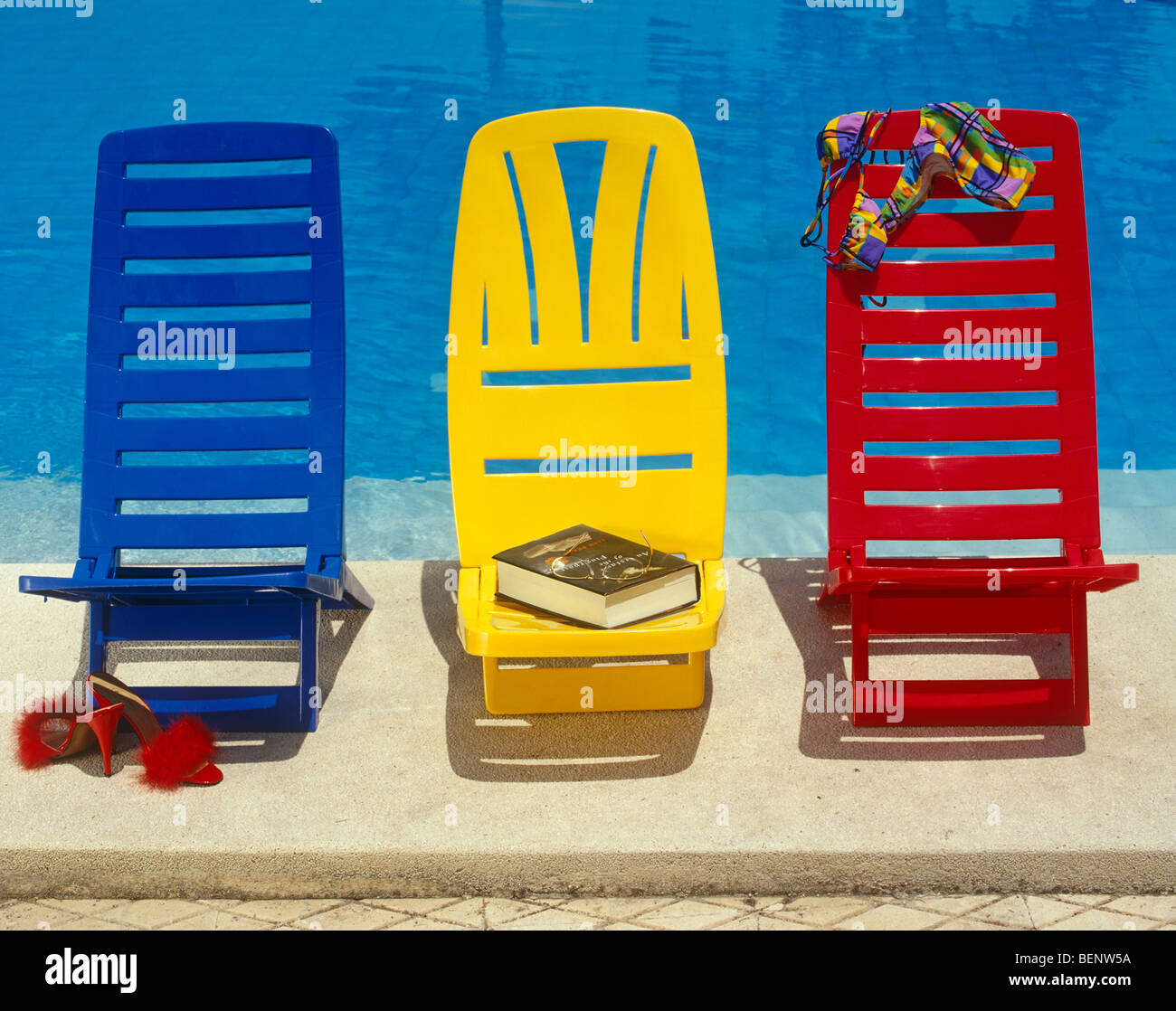 Three colourful swimming pool chairs Stock Photo Alamy