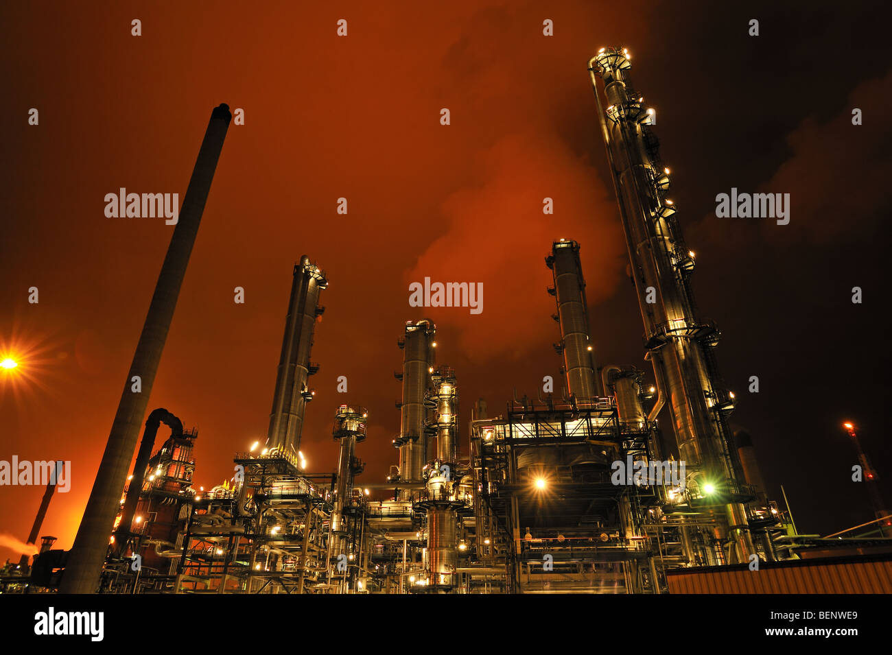 Refinery chimneys of petrochemical industry illuminated at night Stock Photo