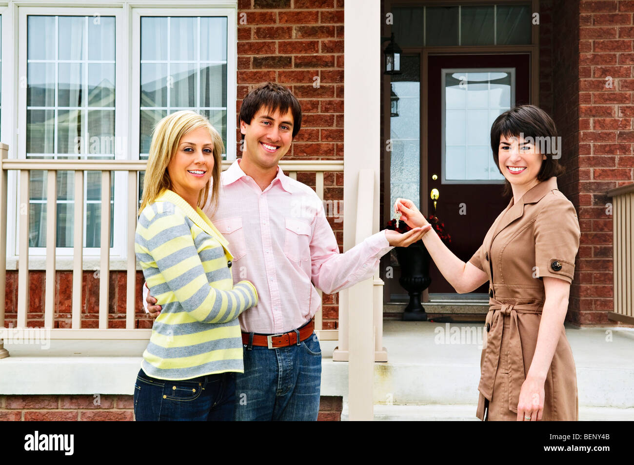 Happy couple getting keys to new house from real estate agent Stock Photo