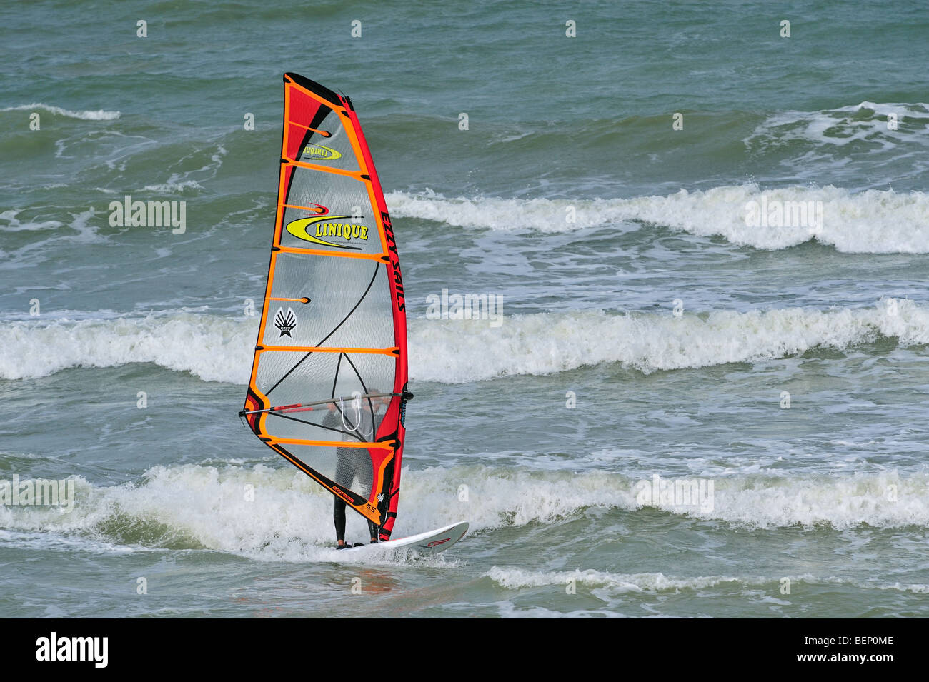 Windsurfer in wetsuit sailing in the surf at sea during storm weather Stock Photo