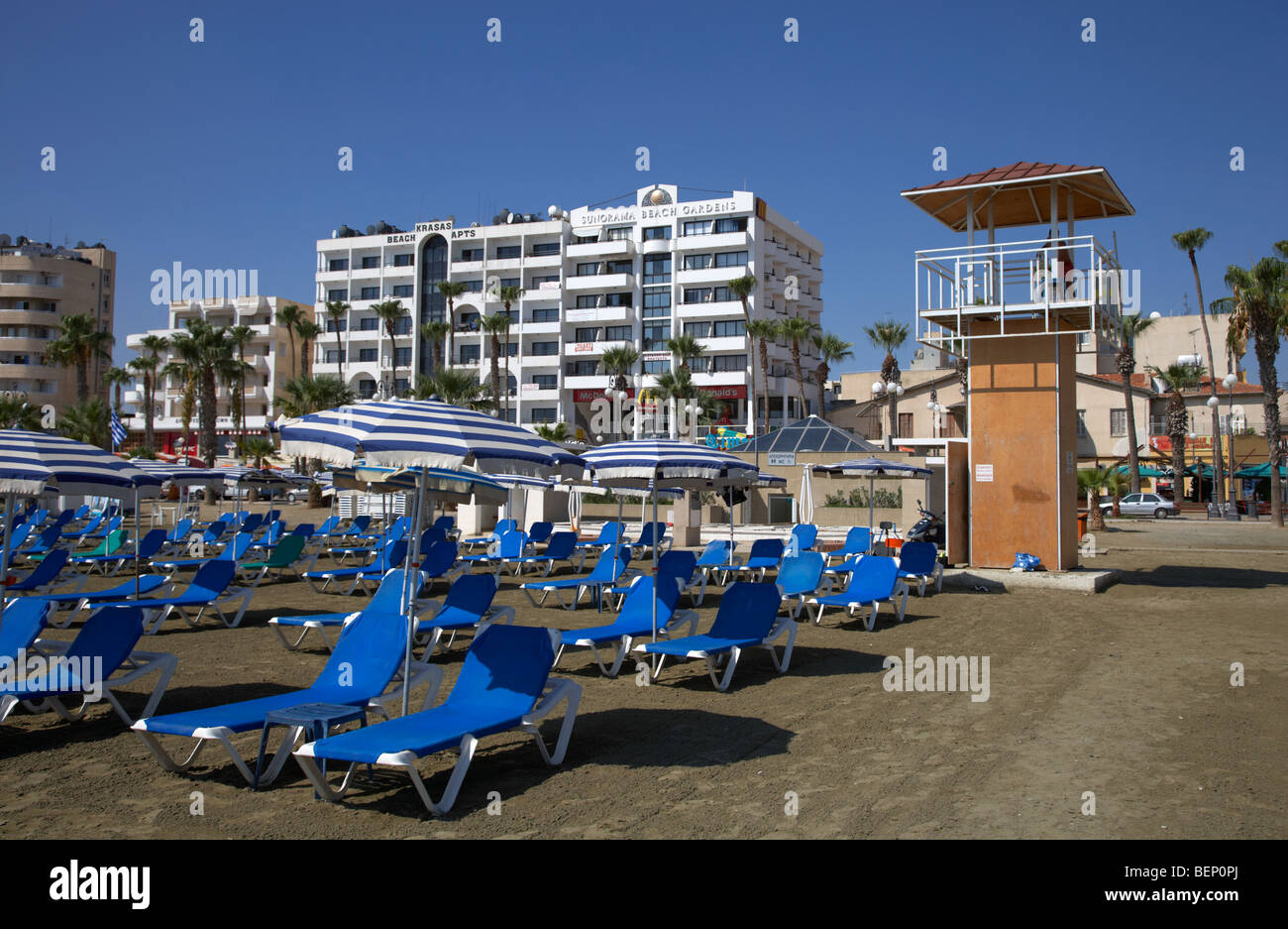 empty sun loungers and lifeguard tower in front of hotels on phinikoudes beach in the town centre of larnaca republic of cyprus Stock Photo