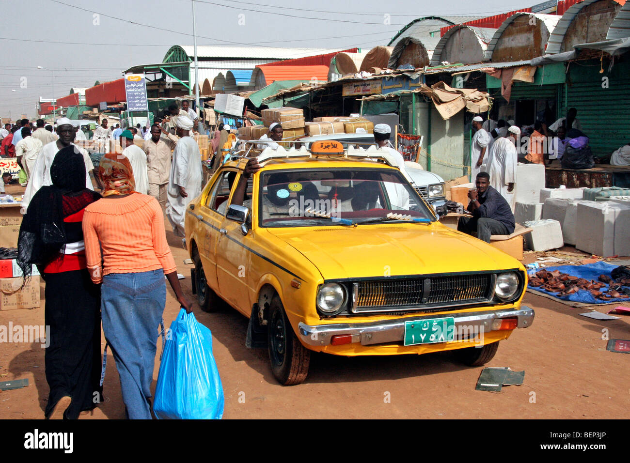 Street scene showing yellow taxi and Nubian people shopping at market in the city Omdurman, Khartoum, Sudan, North Africa Stock Photo