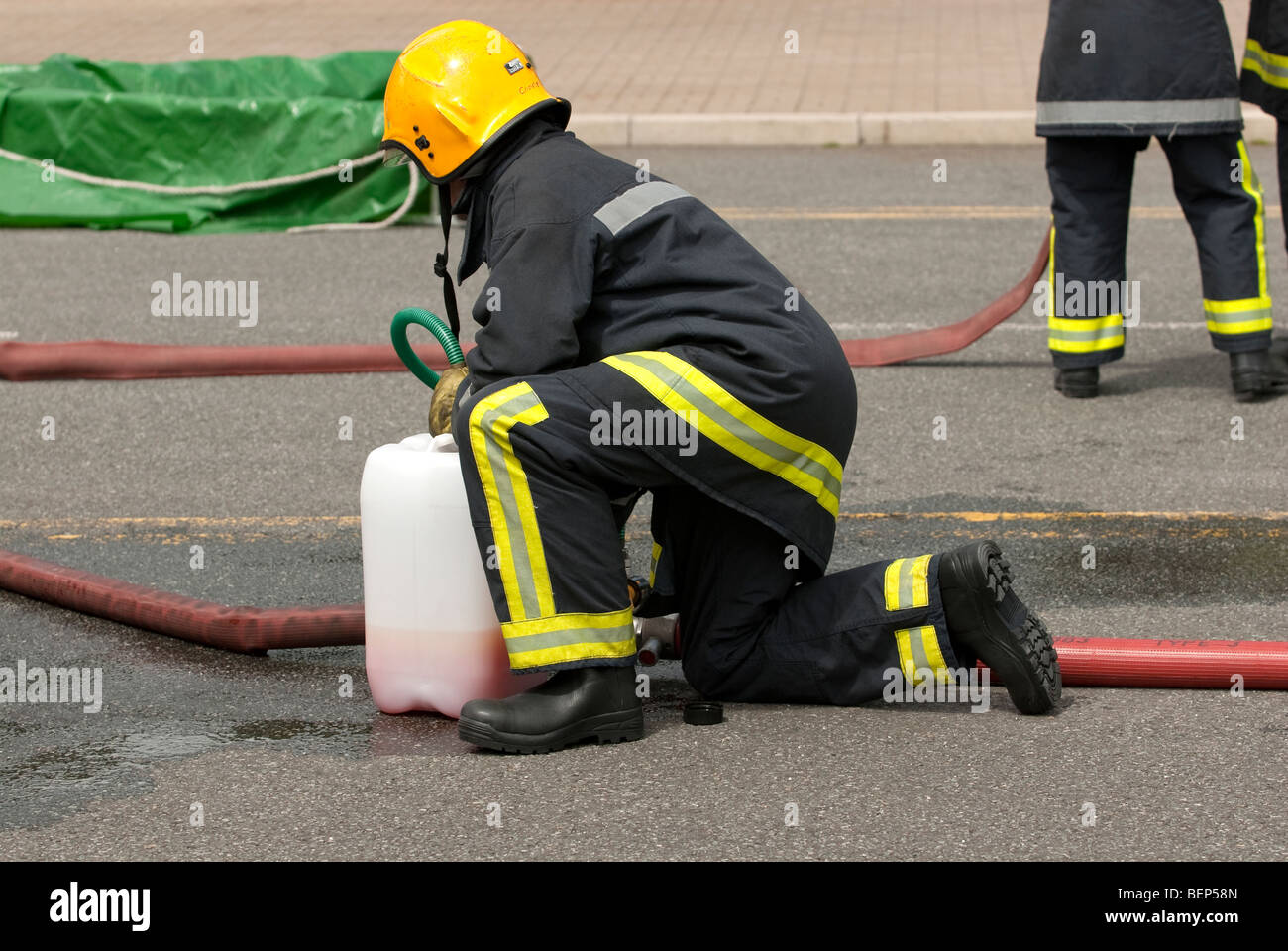 firefighter injecting foam concentrate into main branch hose Stock Photo