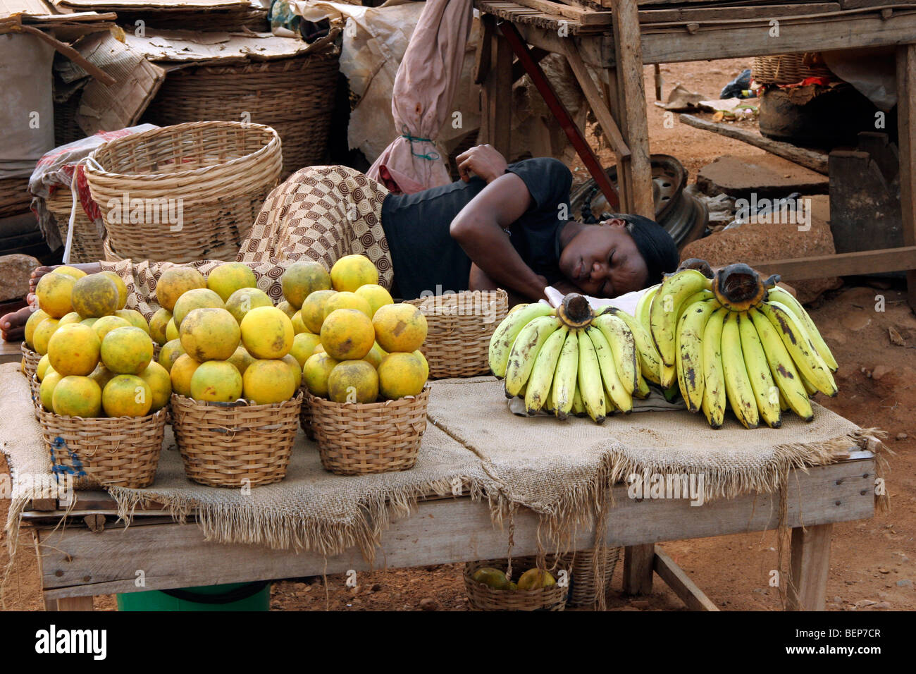 Black woman sleeping at fruit stall on market in the city Kpalimé, Togo