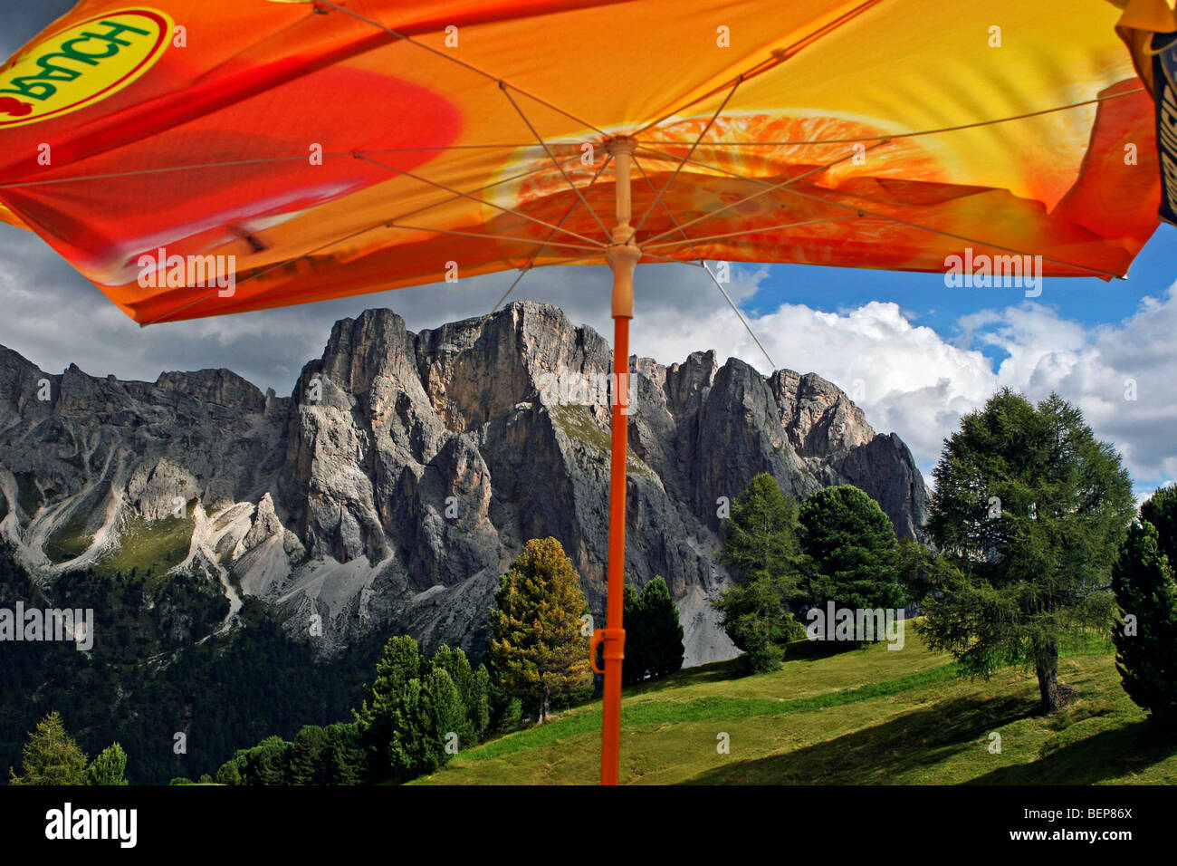 Orange sunshade and view over the mountain range Sass Rigais, Geislergruppe / Geisler group, Dolomites, Italy Stock Photo